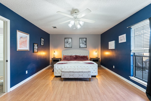 bedroom with a textured ceiling, ceiling fan, and light hardwood / wood-style flooring