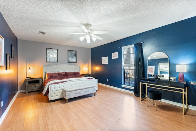 bedroom featuring ceiling fan, light hardwood / wood-style floors, and a textured ceiling