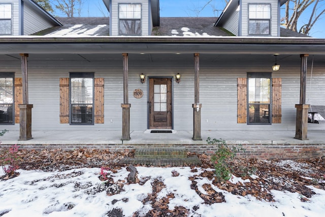 snow covered property entrance with covered porch