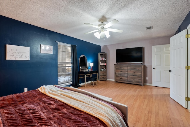 bedroom with a textured ceiling, ceiling fan, and light hardwood / wood-style flooring