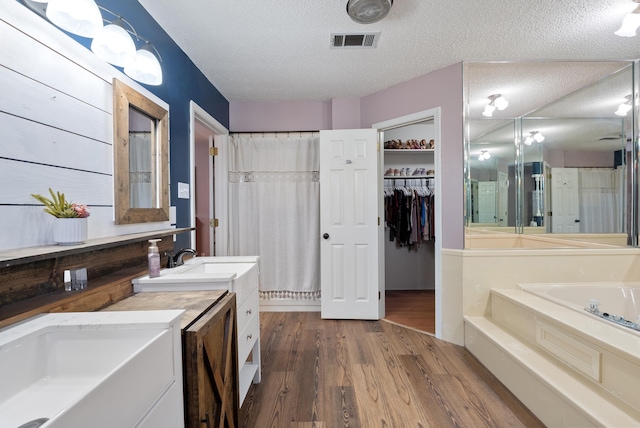 bathroom with a textured ceiling, wood-type flooring, a tub, and vanity