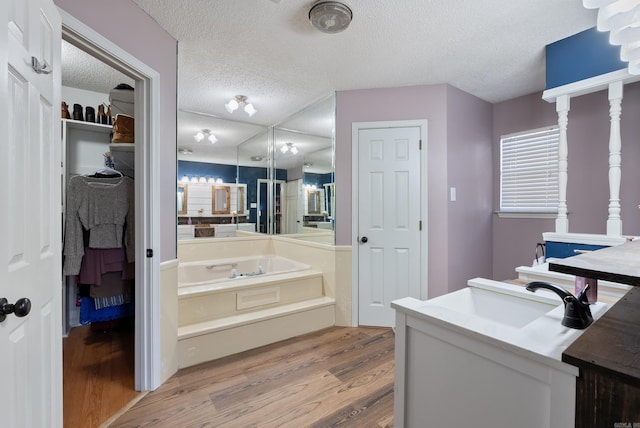 bathroom with a textured ceiling, a bath, hardwood / wood-style floors, and vanity