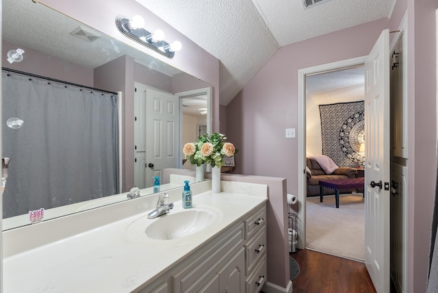 bathroom featuring hardwood / wood-style flooring, a textured ceiling, vanity, and vaulted ceiling