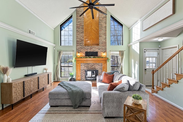 living room with ceiling fan, hardwood / wood-style floors, high vaulted ceiling, and a fireplace