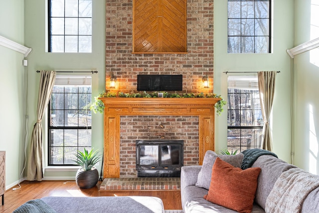 living room featuring a high ceiling, a brick fireplace, and plenty of natural light