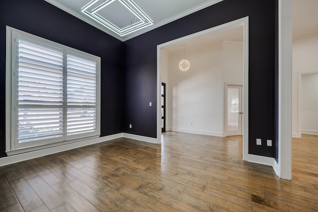 unfurnished room featuring hardwood / wood-style flooring, crown molding, and a notable chandelier