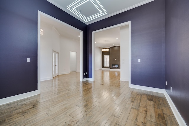 empty room featuring an inviting chandelier, ornamental molding, and hardwood / wood-style flooring