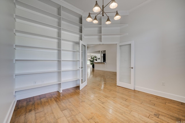 unfurnished dining area with hardwood / wood-style flooring, crown molding, french doors, and a notable chandelier