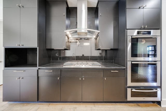 kitchen with stainless steel double oven, extractor fan, gray cabinets, and gas stovetop