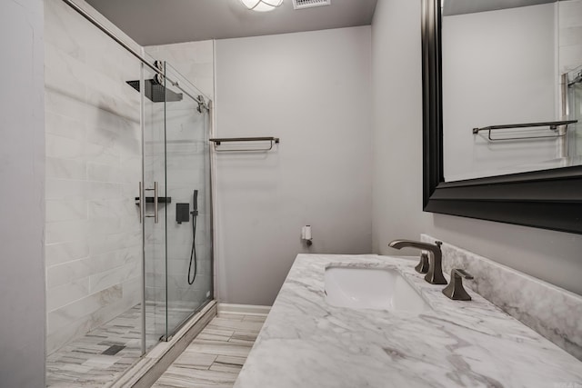 bathroom featuring a shower with shower door and vanity