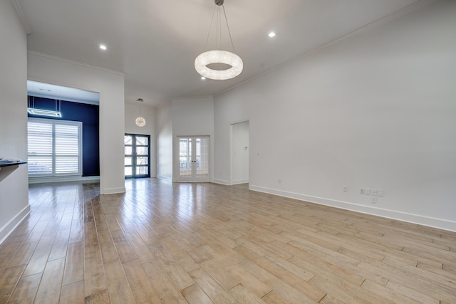 empty room with crown molding, a healthy amount of sunlight, light hardwood / wood-style flooring, and french doors