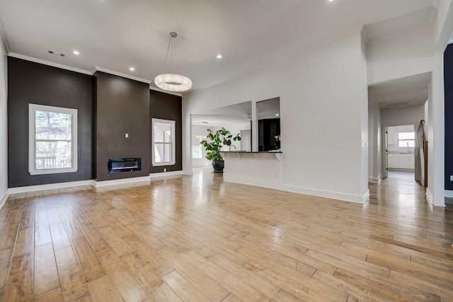 unfurnished living room featuring a fireplace, ornamental molding, and light hardwood / wood-style floors