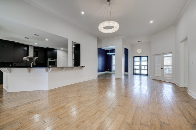 unfurnished living room featuring french doors, sink, crown molding, and light hardwood / wood-style floors