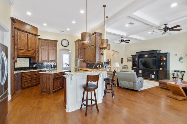 kitchen featuring pendant lighting, beamed ceiling, a kitchen breakfast bar, kitchen peninsula, and coffered ceiling