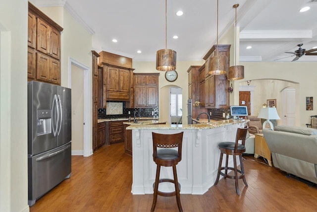 kitchen with light stone countertops, pendant lighting, beamed ceiling, stainless steel fridge, and ceiling fan