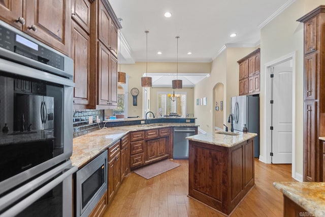 kitchen featuring light hardwood / wood-style floors, kitchen peninsula, stainless steel appliances, decorative light fixtures, and a center island