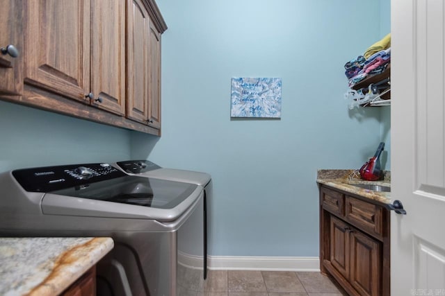 washroom featuring cabinets, sink, washing machine and dryer, and light tile patterned flooring