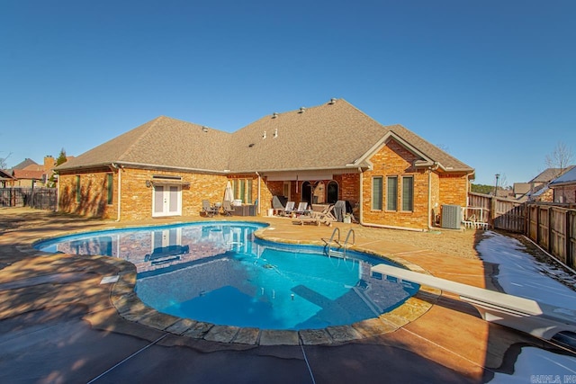 view of swimming pool with a diving board, a patio area, and central AC