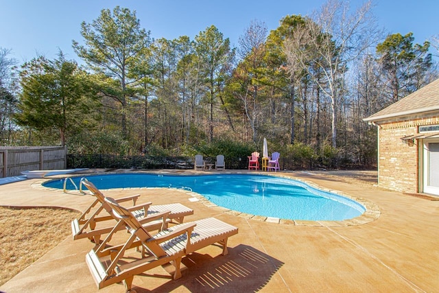 view of pool featuring a diving board and a patio