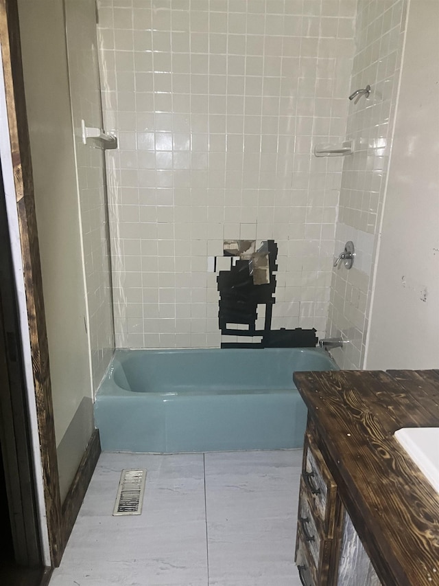 bathroom with tiled shower / bath combo and vanity