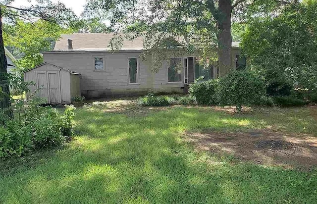 back of property featuring a yard and a storage shed