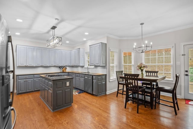 kitchen featuring gray cabinets, a kitchen island, pendant lighting, sink, and stainless steel appliances