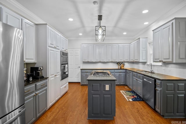 kitchen with appliances with stainless steel finishes, sink, gray cabinetry, a center island, and light wood-type flooring