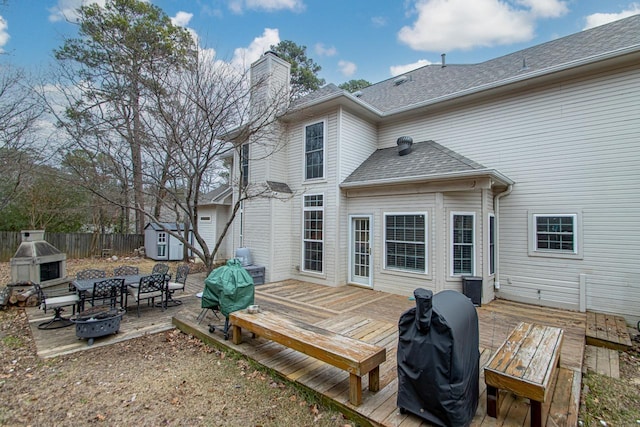 back of property featuring a storage unit, a fireplace, a deck, and a fire pit