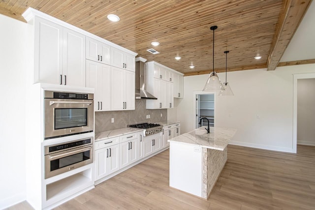 kitchen featuring an island with sink, wall chimney range hood, white cabinetry, and beamed ceiling