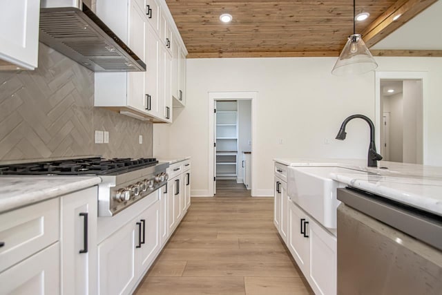 kitchen with wood ceiling, stainless steel appliances, hanging light fixtures, wall chimney range hood, and light stone counters