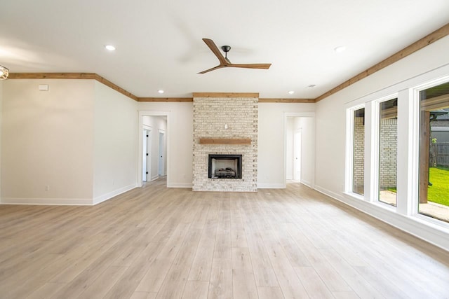 unfurnished living room featuring a brick fireplace, light hardwood / wood-style flooring, ornamental molding, and ceiling fan