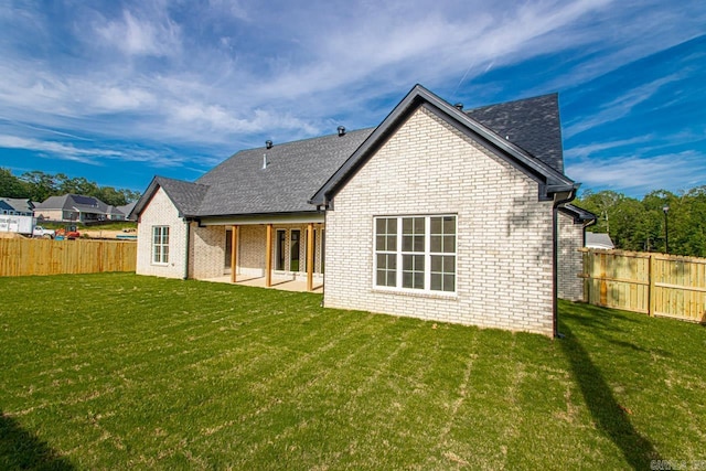 back of property with a patio area and a lawn