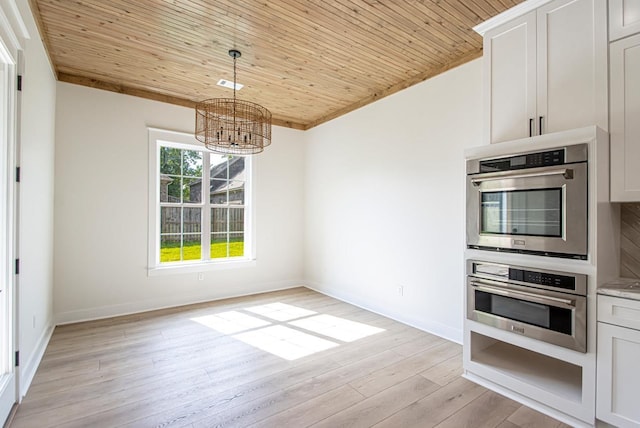 kitchen featuring wooden ceiling, white cabinetry, stainless steel double oven, and an inviting chandelier