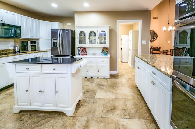 kitchen with decorative light fixtures, a chandelier, black appliances, white cabinets, and a center island