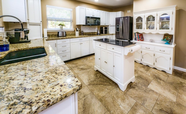 kitchen with light stone counters, sink, white cabinets, and black appliances