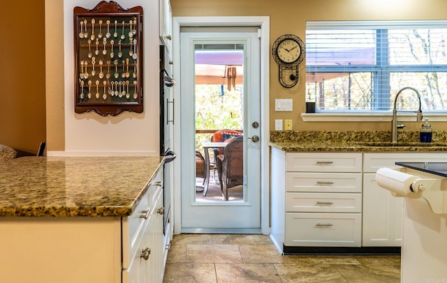 kitchen featuring sink, white cabinetry, and dark stone countertops