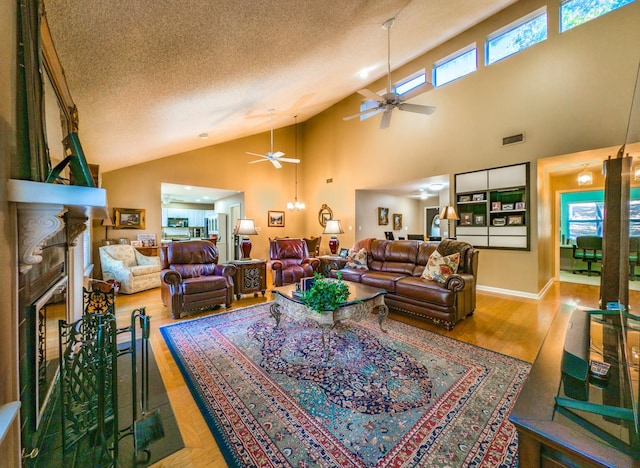 living room featuring a wealth of natural light, a large fireplace, a textured ceiling, and light wood-type flooring