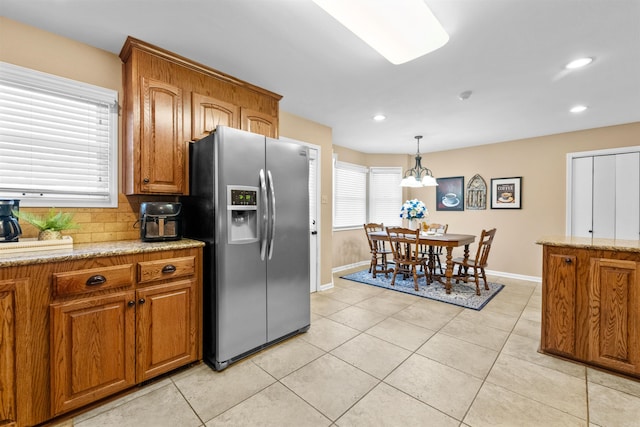 kitchen featuring light tile patterned floors, light stone countertops, stainless steel fridge with ice dispenser, and an inviting chandelier