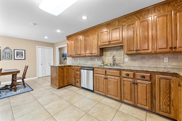 kitchen featuring tasteful backsplash, dishwasher, sink, light tile patterned flooring, and light stone counters