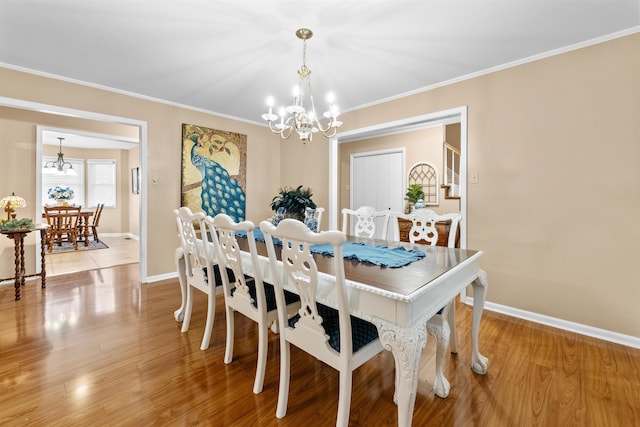 dining area featuring crown molding, an inviting chandelier, and light hardwood / wood-style floors