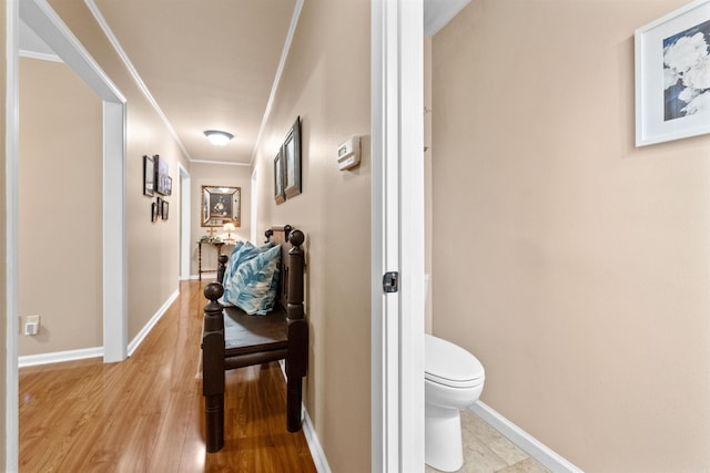 corridor with ornamental molding and light hardwood / wood-style floors