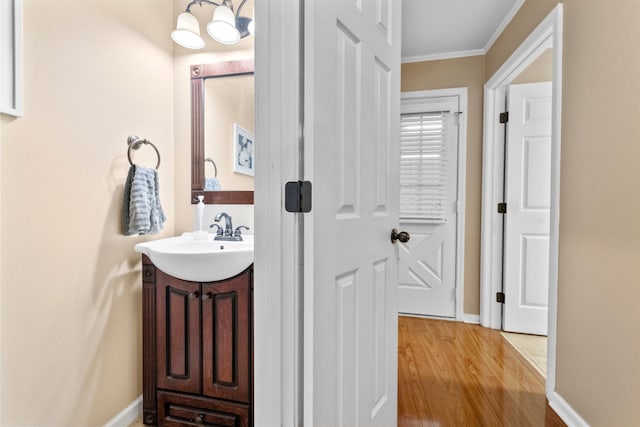 bathroom featuring an inviting chandelier, ornamental molding, wood-type flooring, and vanity