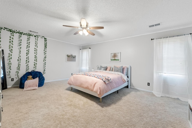 carpeted bedroom with ceiling fan, crown molding, multiple windows, and a textured ceiling