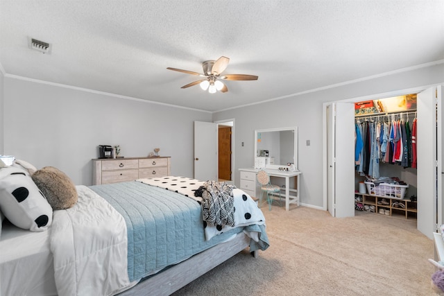 bedroom with a textured ceiling, a closet, ornamental molding, ceiling fan, and light colored carpet