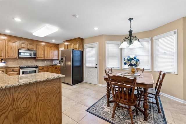 kitchen featuring a notable chandelier, pendant lighting, decorative backsplash, stainless steel appliances, and light tile patterned floors