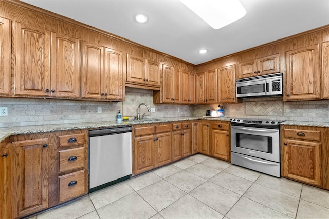 kitchen featuring tasteful backsplash, sink, light stone countertops, stainless steel appliances, and light tile patterned floors