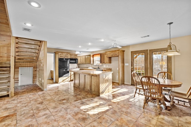 kitchen featuring black appliances, ceiling fan, sink, and a center island