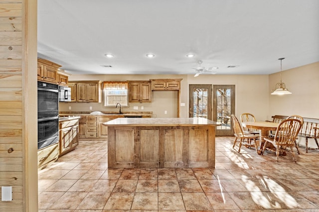 kitchen featuring a kitchen island, decorative light fixtures, double oven, light tile patterned flooring, and ceiling fan