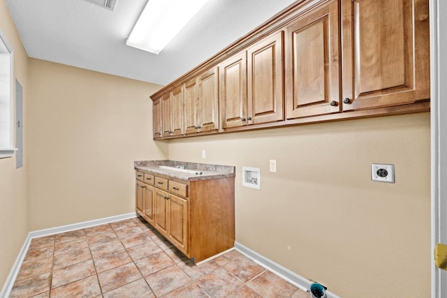 laundry room with sink, light tile patterned flooring, hookup for a washing machine, electric dryer hookup, and cabinets