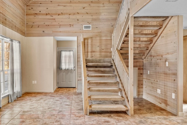 stairs with a wealth of natural light, wooden walls, and high vaulted ceiling